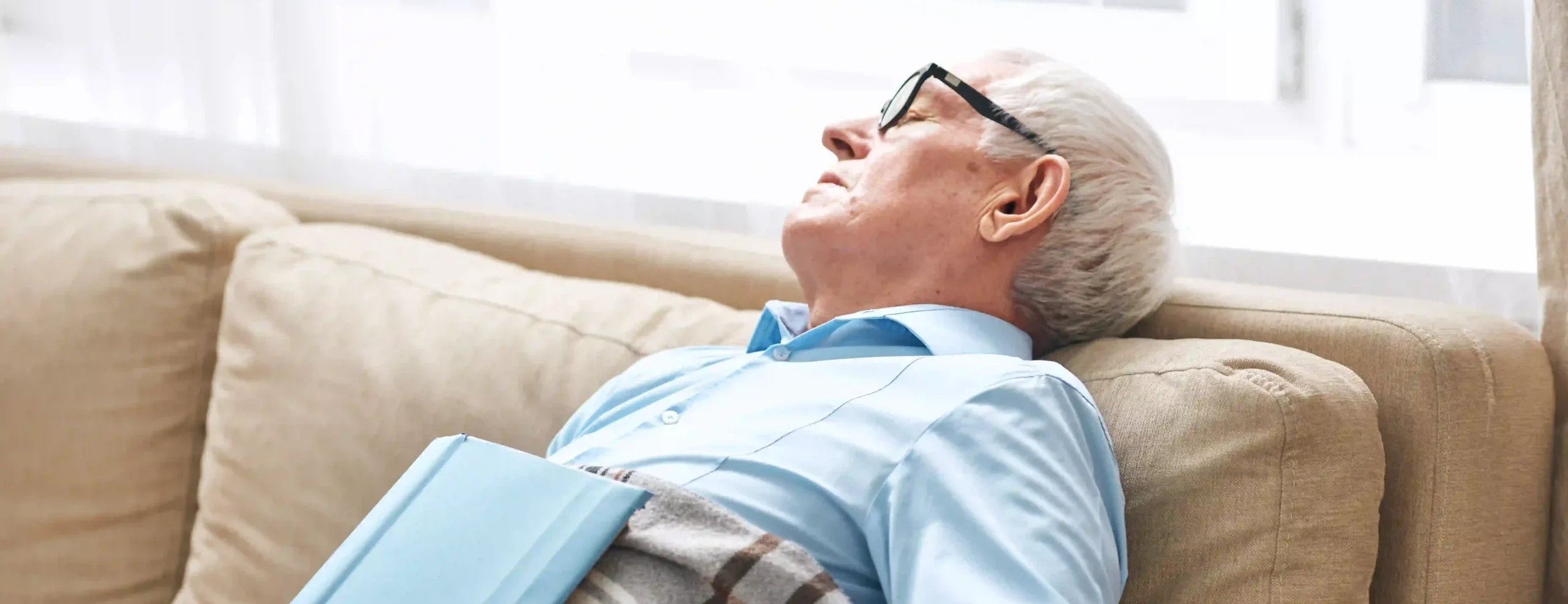 tired-senior-man-covered-with-plaid-napping-on-cou-2025-03-18-15-08-57-utc